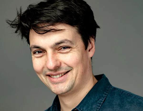 Portrait d'un homme souriant, regardant la caméra, chemise bleue.