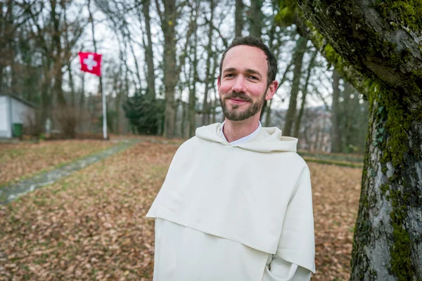 Portrait d'un moine souriant en Suisse, drapeau en arrière-plan
