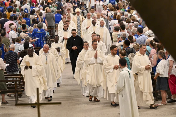 Procession religieuse à Lourdes avec prêtres en blanc.