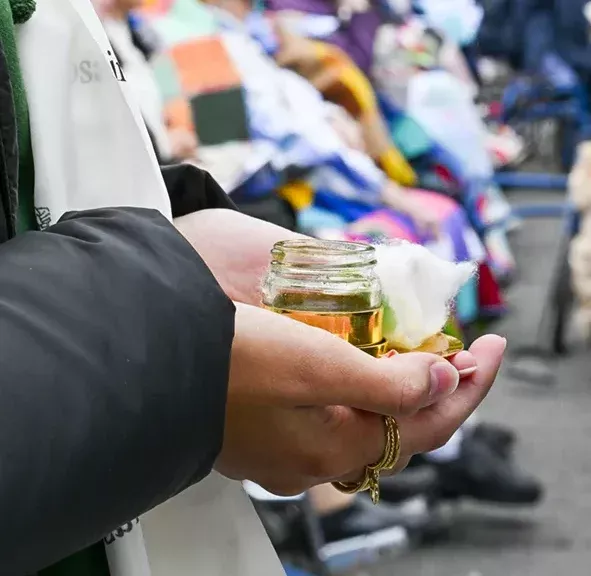 Mains tenant un bocal d'huile lors d'une cérémonie