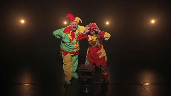 Deux clowns en costumes sur scène avec projecteurs
