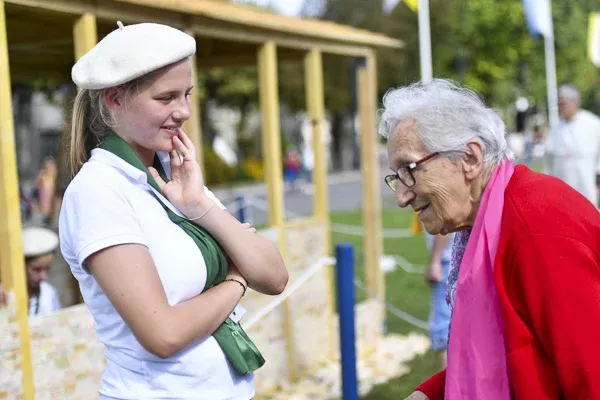 Jeune femme parlant avec une personne âgée souriante.