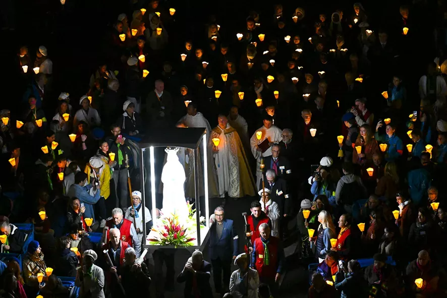 Foule avec statue de Marie et bougies à Lourdes