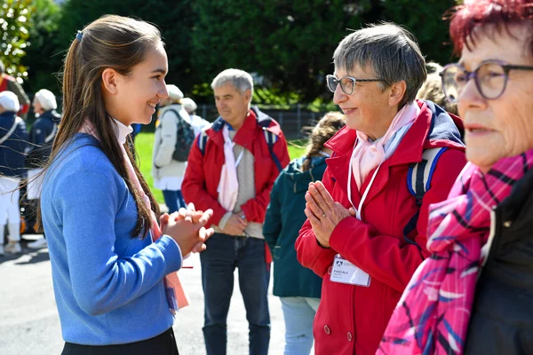 Femme et jeune fille discutant avec un groupe derrière