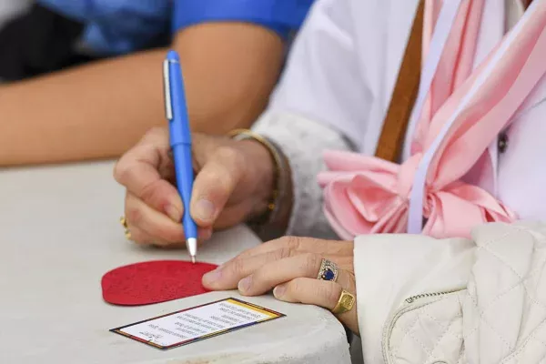 Personne écrivant sur une carte rouge avec un stylo bleu