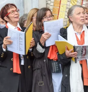 Groupe femmes âgées chantant avec partitions en extérieur.