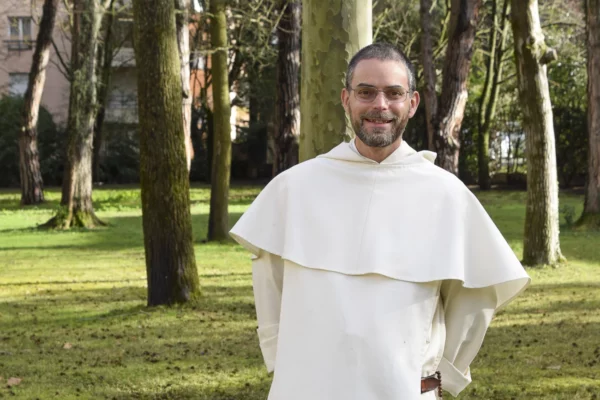 Portrait d'un moine dominicain souriant en habit blanc dans un jardin