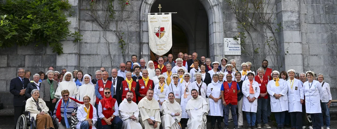 Groupe de pèlerins et hospitaliers de l'Hospitalité du Rosaire devant la Chapelle Notre-Dame des Douleurs à Lourdes.